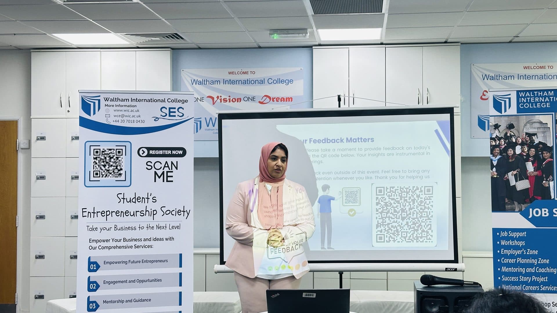 A WIC staff member speaking at the front of the room next to the Student's Entrepreneurship Society banner
