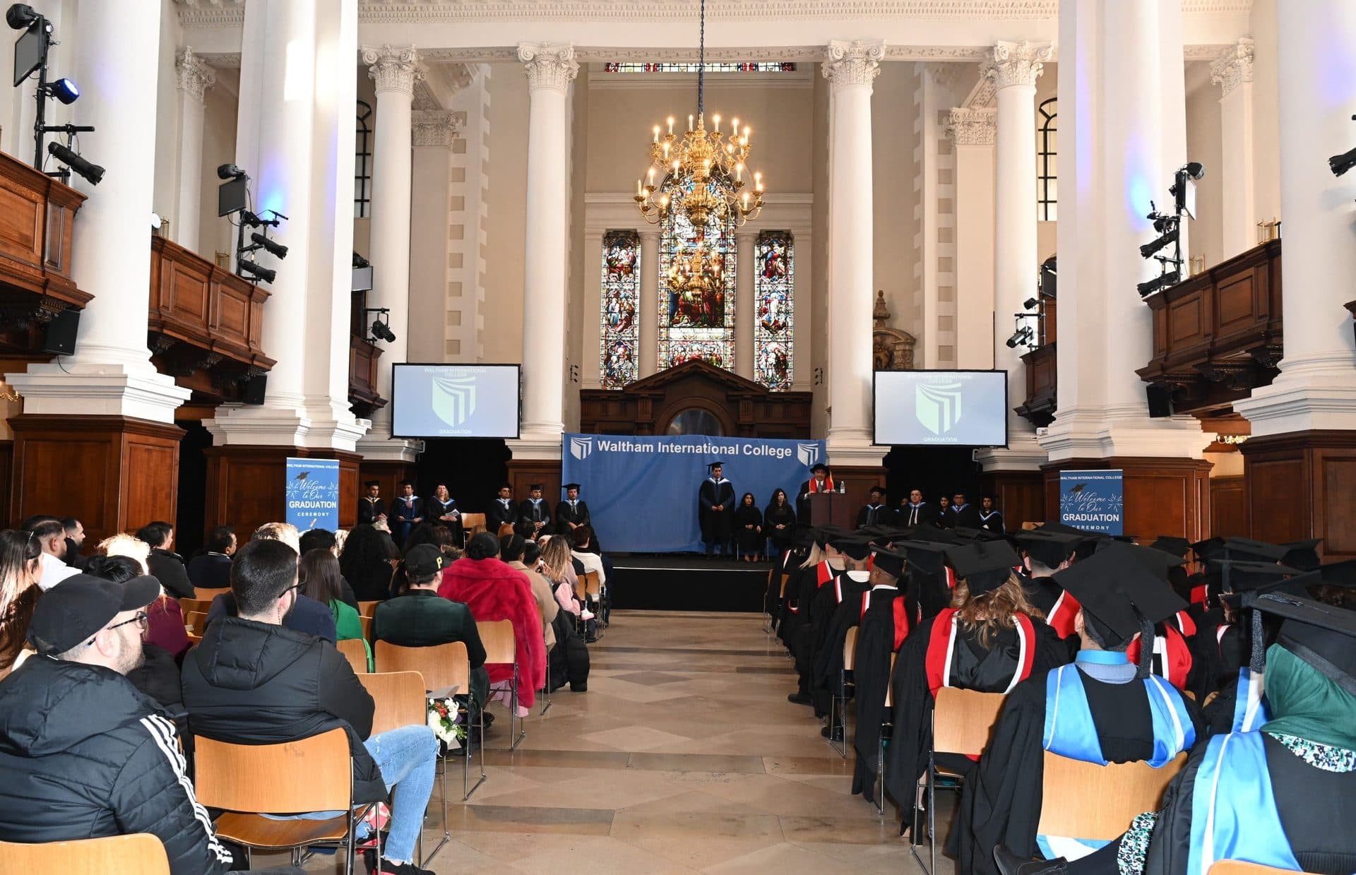 A wide view of the Class of 2024 ceremony hall, with the WIC banner on stage and the audience seated