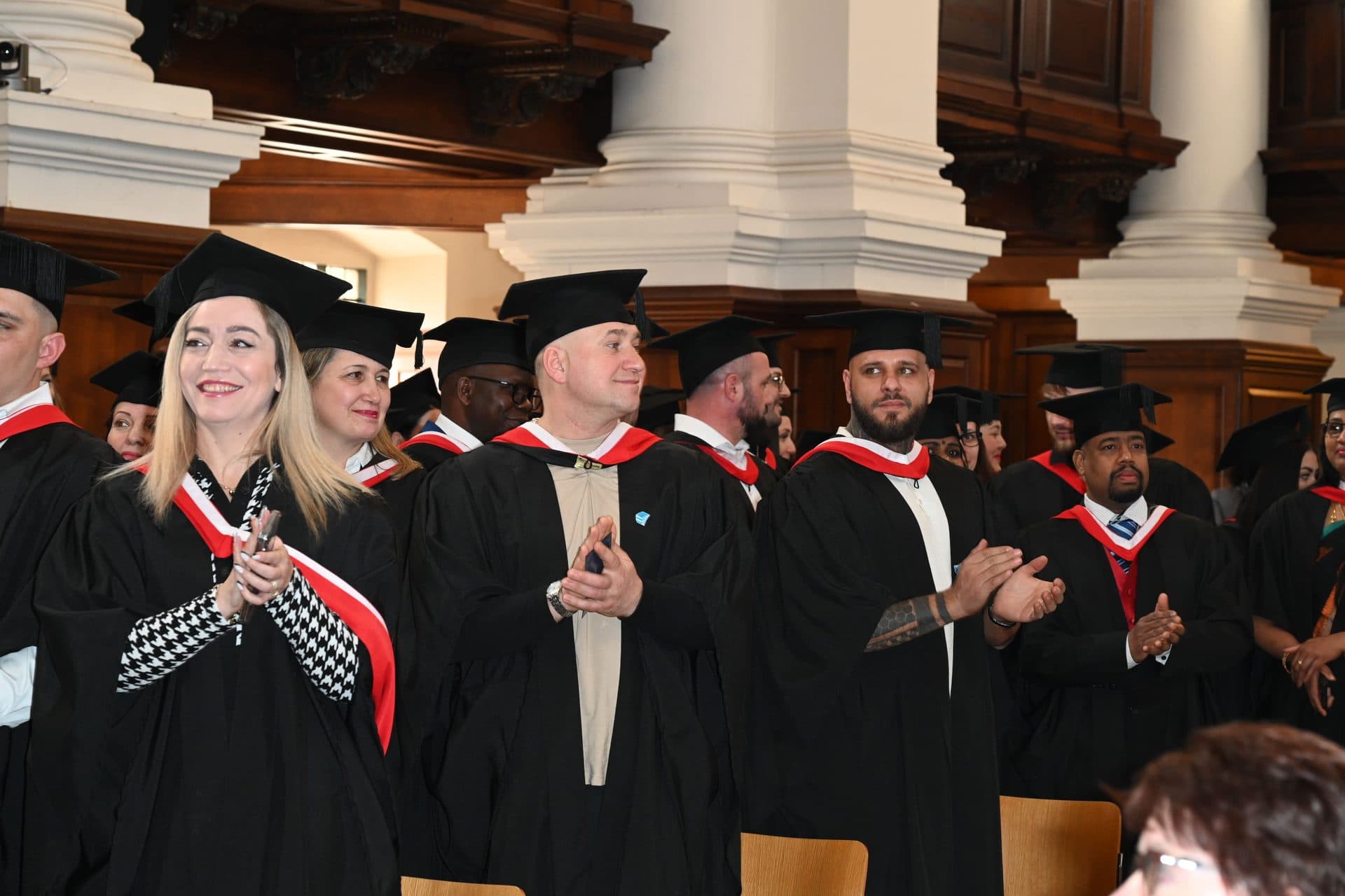Graduates and staff in academic gowns applauding at the Class of 2024 ceremony