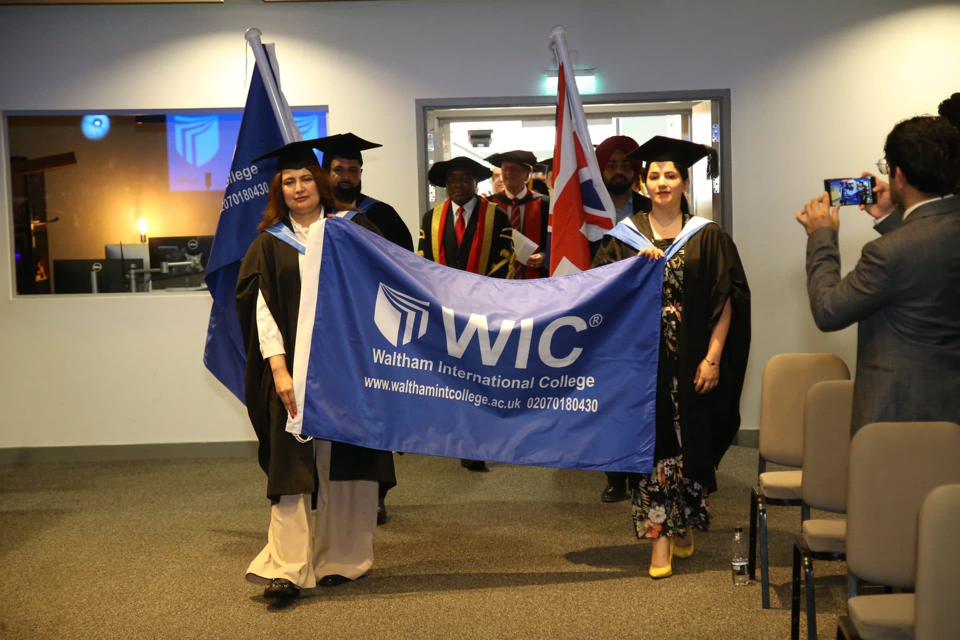 WIC graduates and staff leading the Class of 2026 procession with the WIC banner