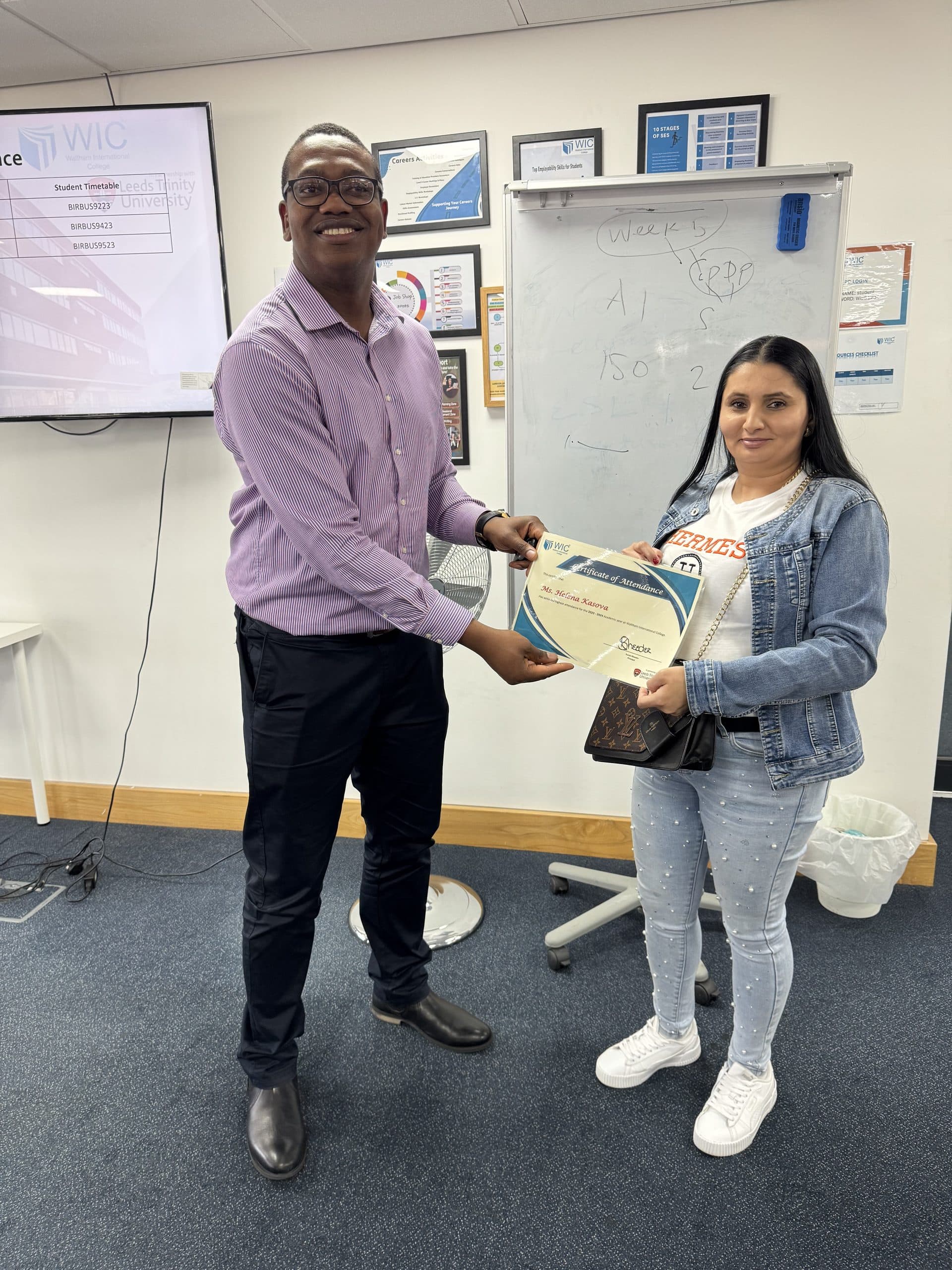 A WIC staff member handing a Certificate of Attendance to a student in an office