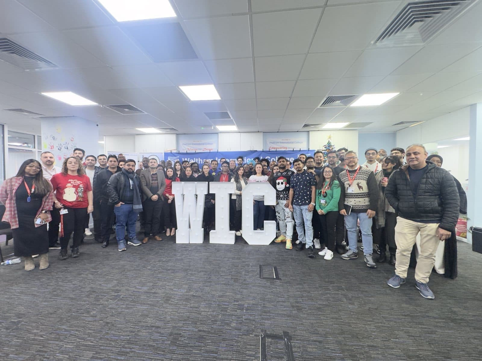 A large group of WIC staff gathered around illuminated 'WIC' letter decorations