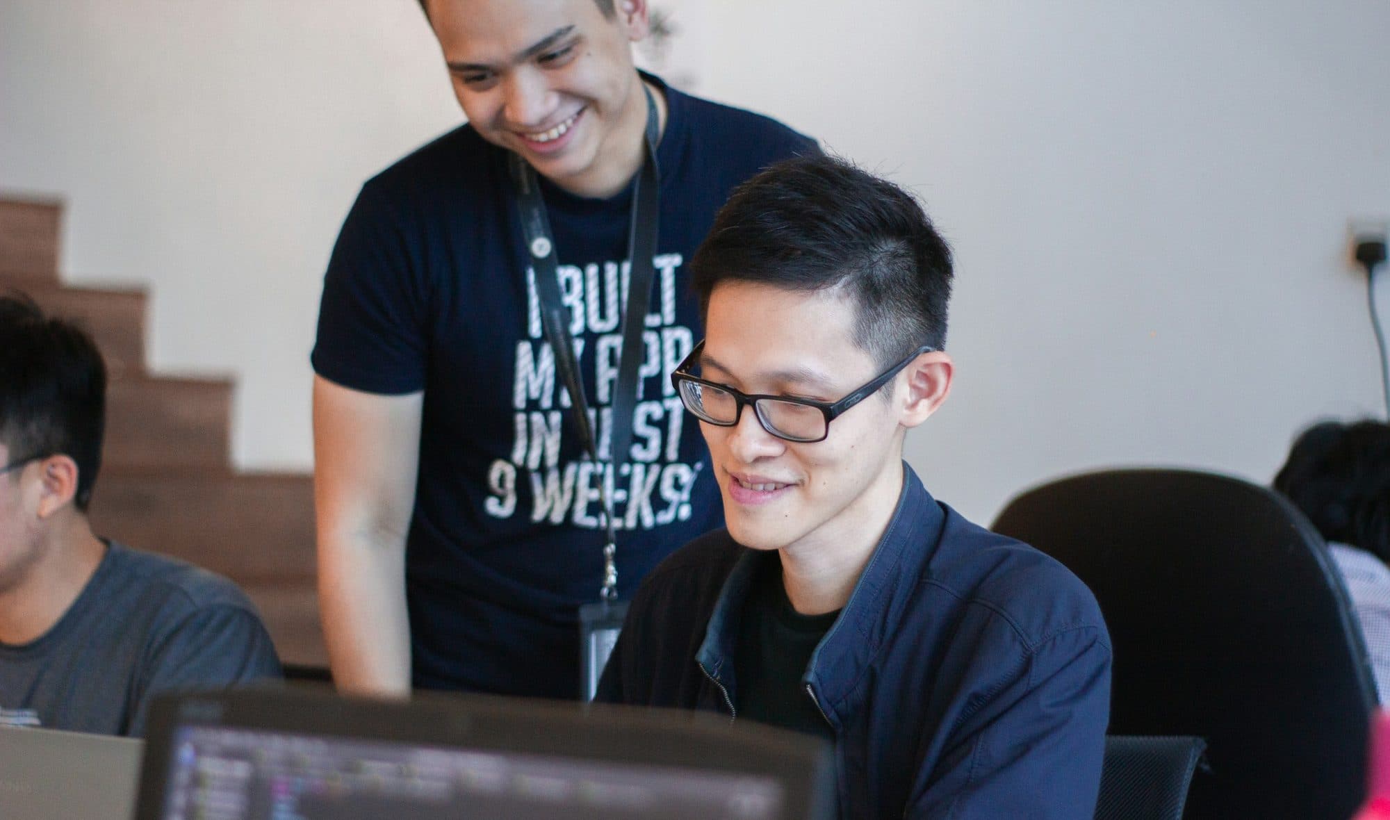 A mentor supporting a student one-to-one at a laptop