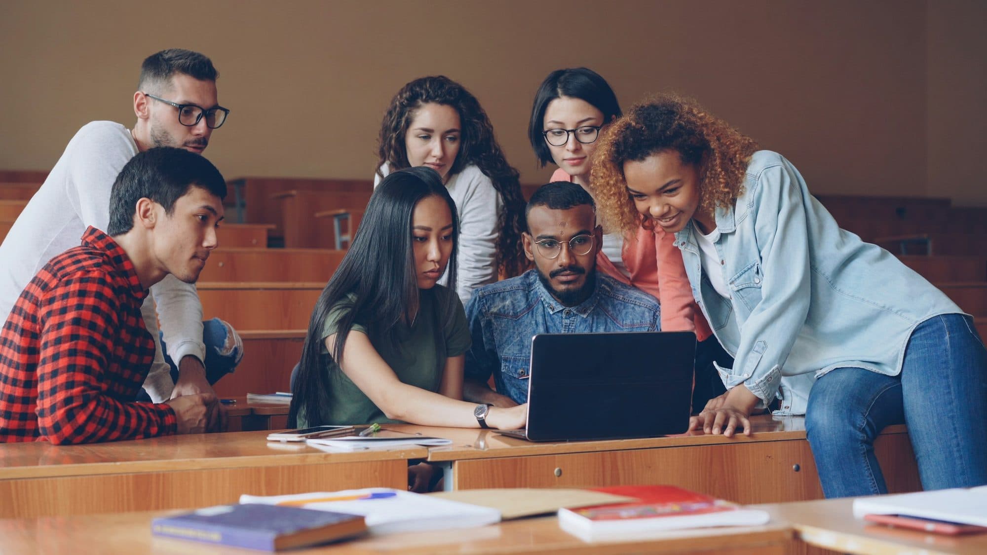 Business students collaborating over a laptop in a lecture hall